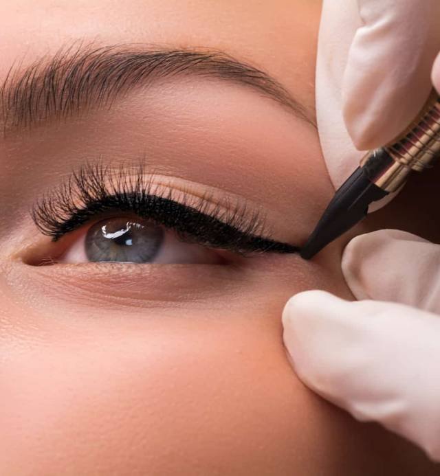 Permanent eye makeup close up shot. Cosmetologist applying tattooing of eyes. Makeup eyeliner procedure